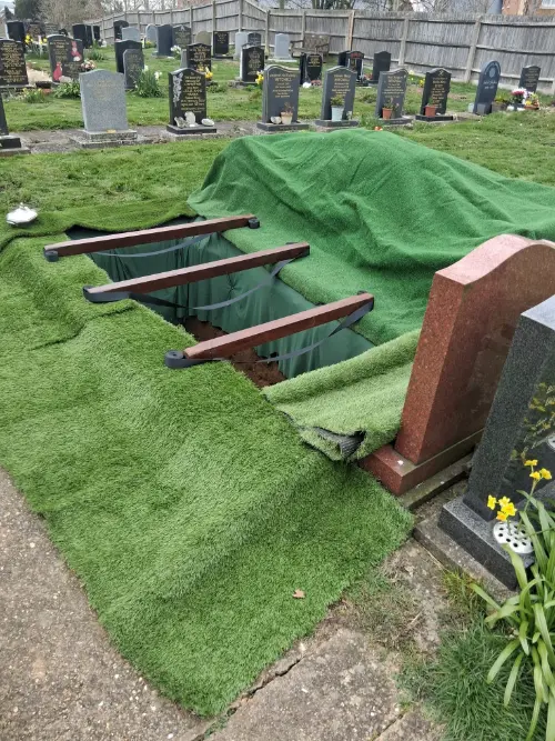 Grave site prepared with grave draped with artificial grass